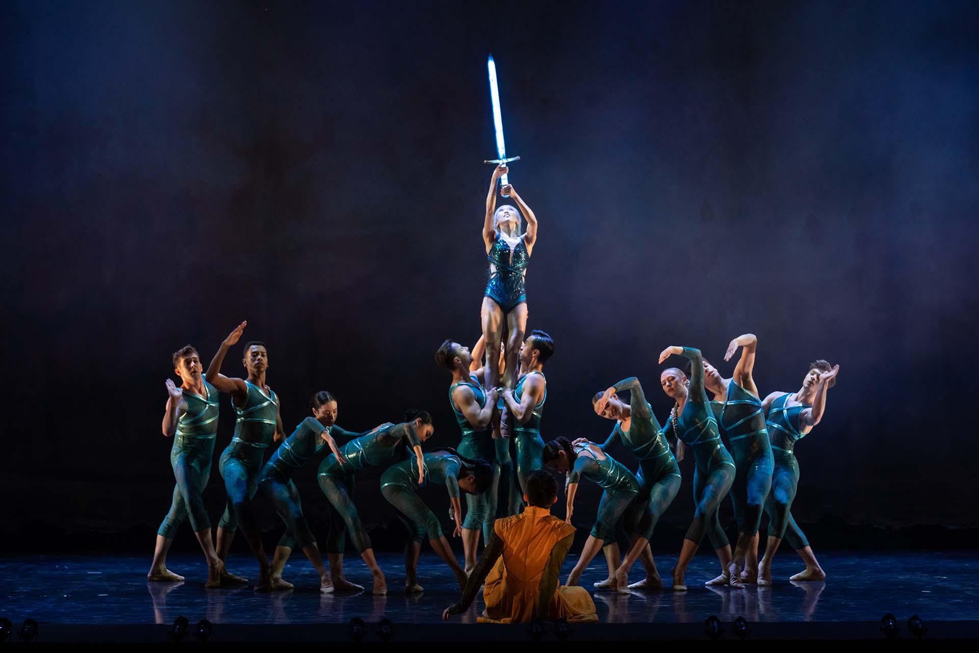 The Lady of the Lake, surrounded by water, holds the fabled Excalibur high above her